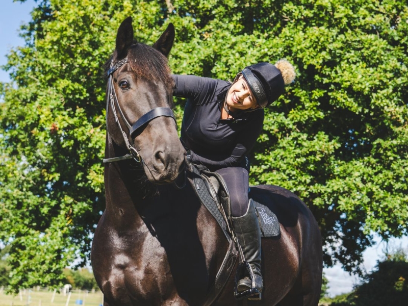 Photograph of a horse rider patting horse.